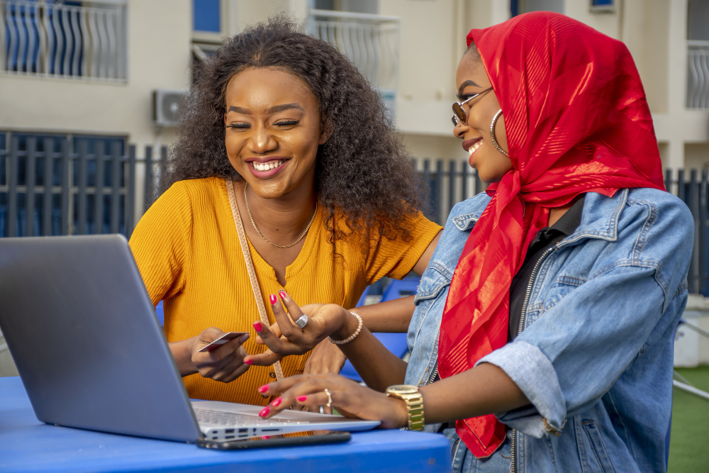 closeup-shot-two-cheerful-young-african-ladies-laptop